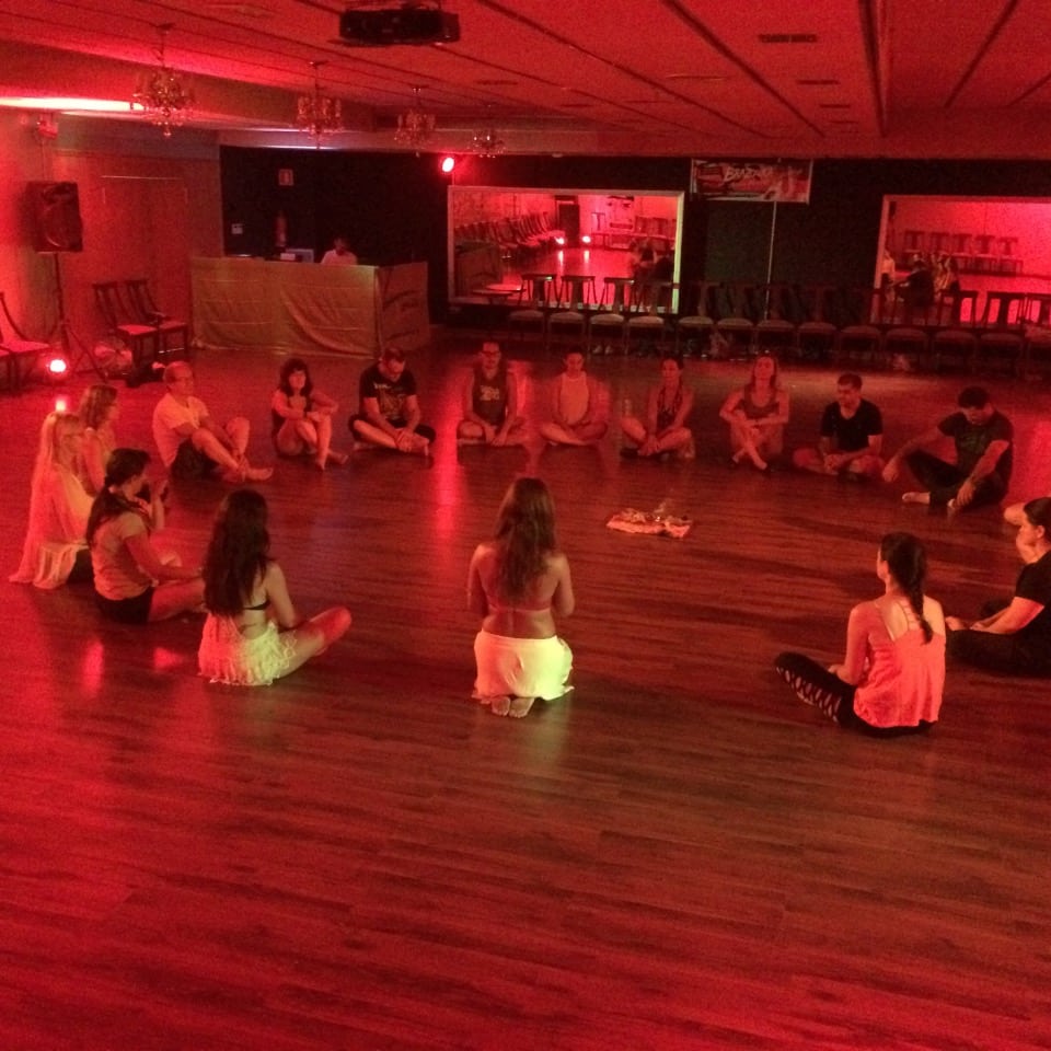 Dancers seated in a circle on the dance floor during the soul consciousness workshop